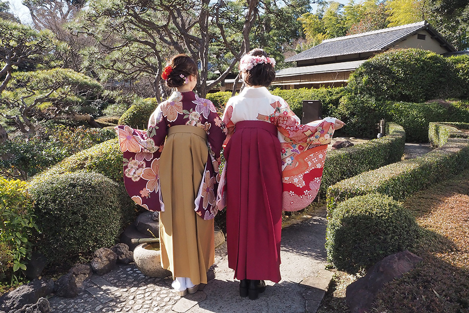日本庭園で記念撮影をする袴姿の2人の女性の様子