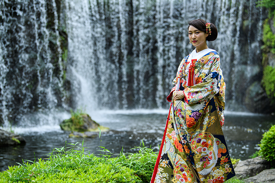 日本庭園の大滝の前で佇む和装の新婦